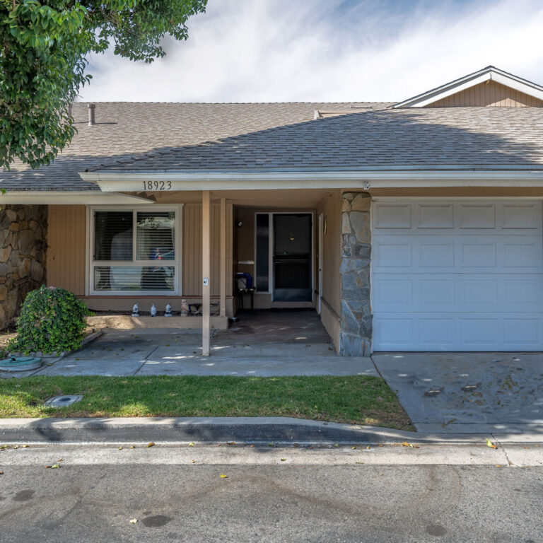 Front of a brown house showing two garages.