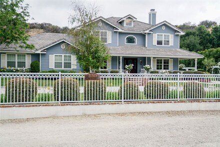 Blue and white two-story house with white gate.